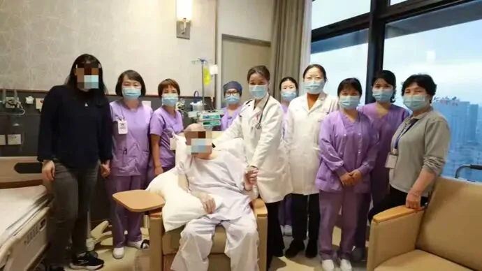 Daniel with family and Jiahui healthcare staff in a ward; his face was obscured in the original photograph