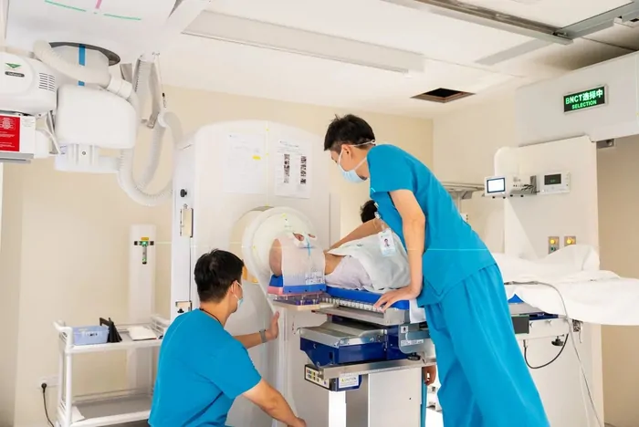 Healthcare staff adjust the patient's position in a BNCT treatment room