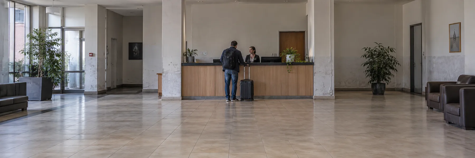 A traveler with luggage at an accommodation reception desk