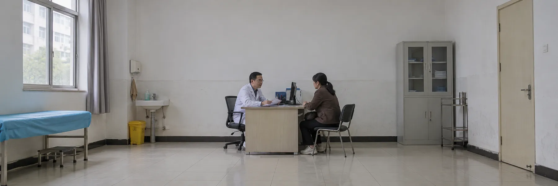A patient speaking with a doctor in an ordinary consultation room, with medical documents on the desk